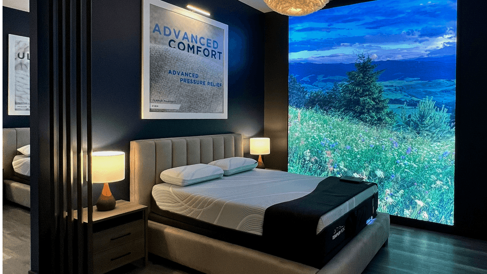 A Tempur-Pedic Retail Showroom Sleep Pod with a Scenic Background Showing Trees, Long Grass, and Flowers