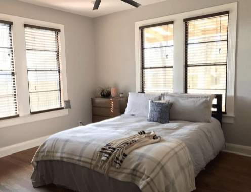 Bedroom with gray walls, hardwood floors, gray bedding, and large windows