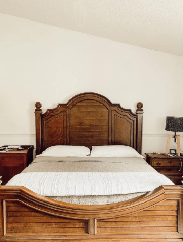 Decorated bed with white bedding on brown wooden bedframe