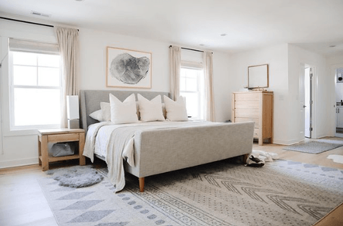 Decorated bedroom with light gray rug, gray bedframe, and white bedding