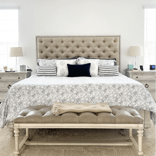 Decorated room with black and white bedding on mattress and tan bench with tan headboard