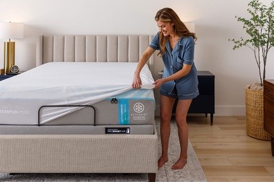 Woman wearing pajamas putting sheets on mattress