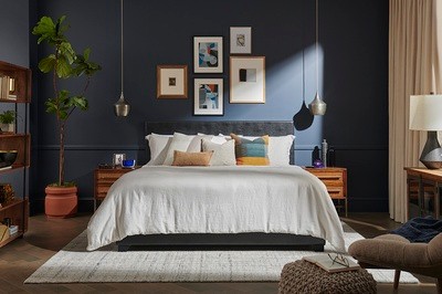 Decorated room with styled bed, throw pillows, photos, plants.