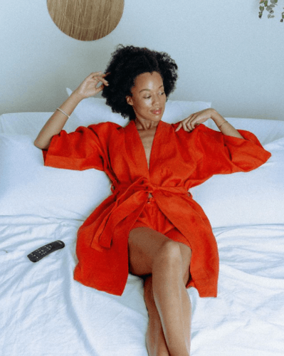 Instagram image of black girl in om showing woman in red pajamas sitting on mattress smiling