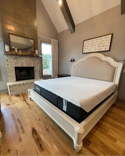 ProAdapt soft TempurPedic mattress on a white wooden bedframe with hardwood flooring and a brick fireplace to the side of the best