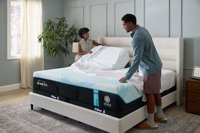 Couple putting sheets on TEMPUR-Breeze mattress in decorated room