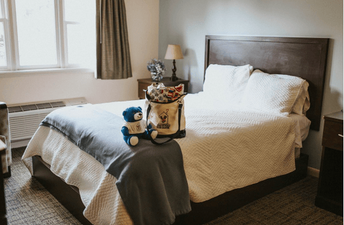 Ronald McDonald House Room showing bed with stuffed bear and giftbag sitting on bed