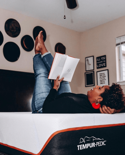 Woman Laying on Bed Reading With Feet Propped Up in Bedroom