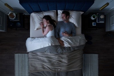 Birdseye view of couple asleep in bed in a dark room