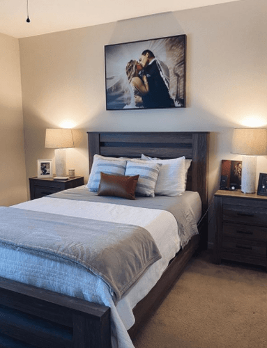 bedroom with decorated bed, matching nightstands and lamps, and a photo of married couple on wall.png