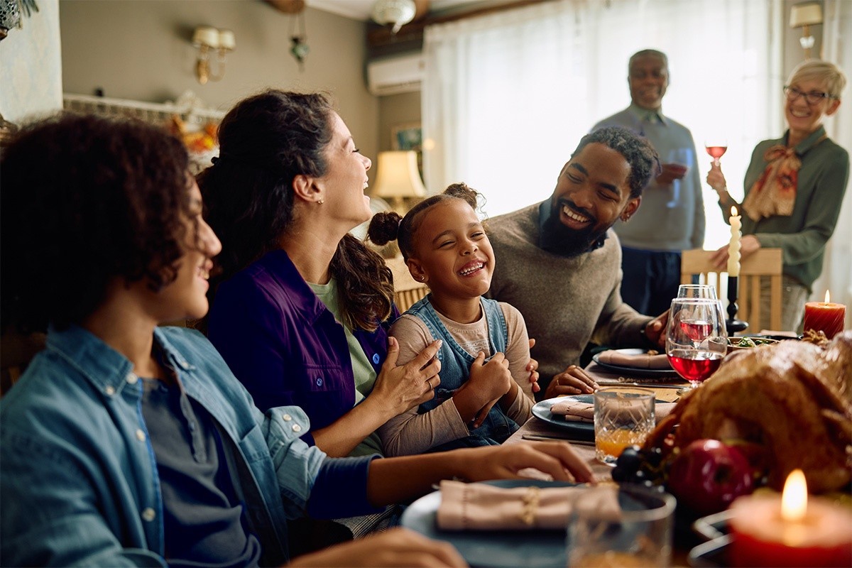 a smiling family gathered around their dining room table for a large meal