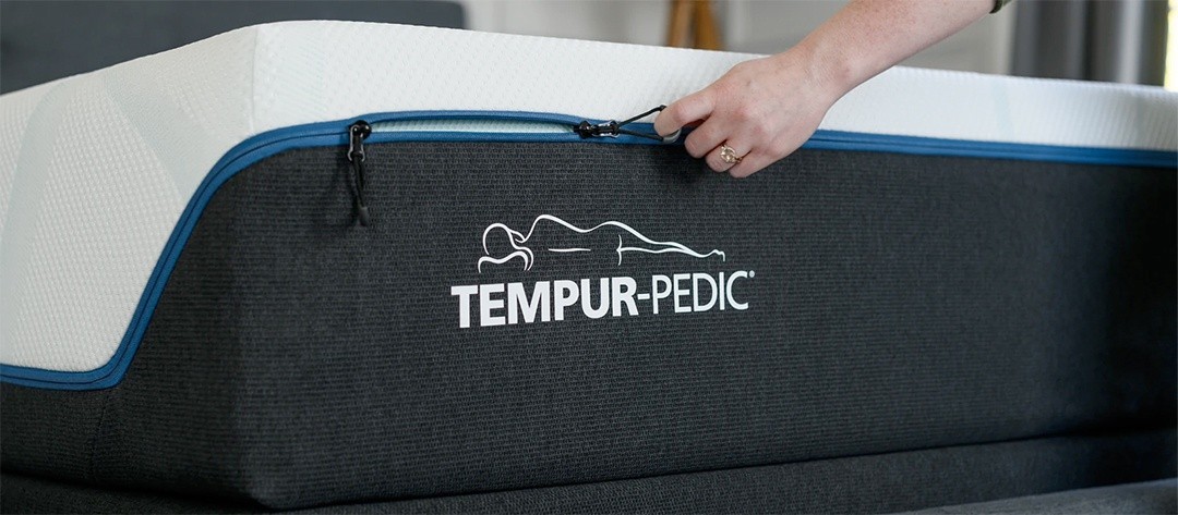 a hand unzipping the top cover of a mattress