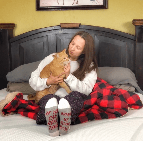 Woman Holding Cat on a Styled Bed in Bedroom