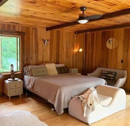 made bed within a wooden room with a white night stand and white fur rug on the ground
