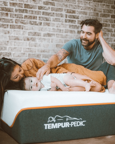 Man, woman and baby laying on mattress