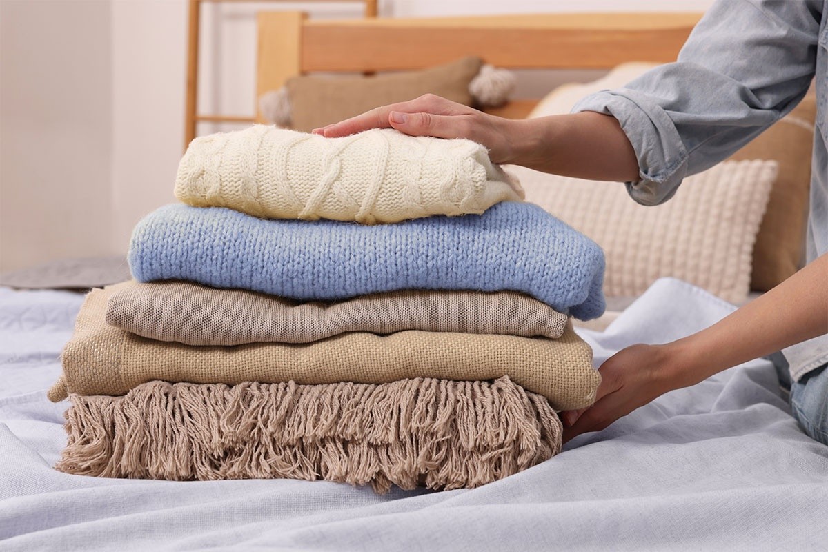 A stack of folded blankets on a bed