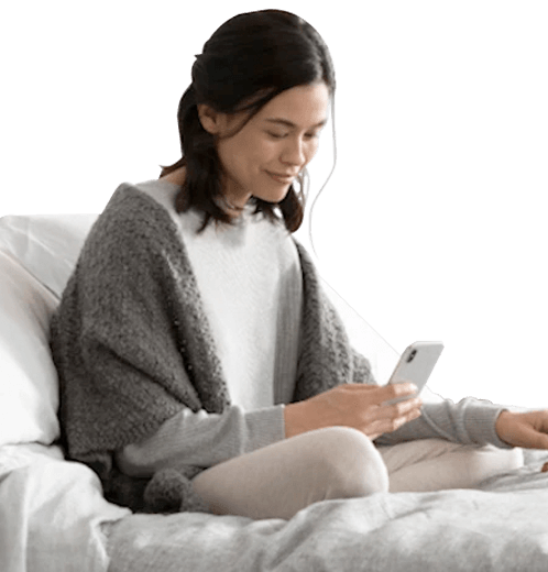 A girl sitting on a bed looking at her phone