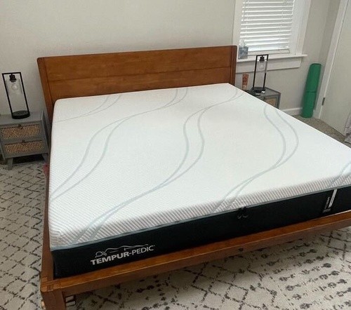 Tempur-Pedic Breeze mattress sitting on a wooden bed frame with a night stand on each side